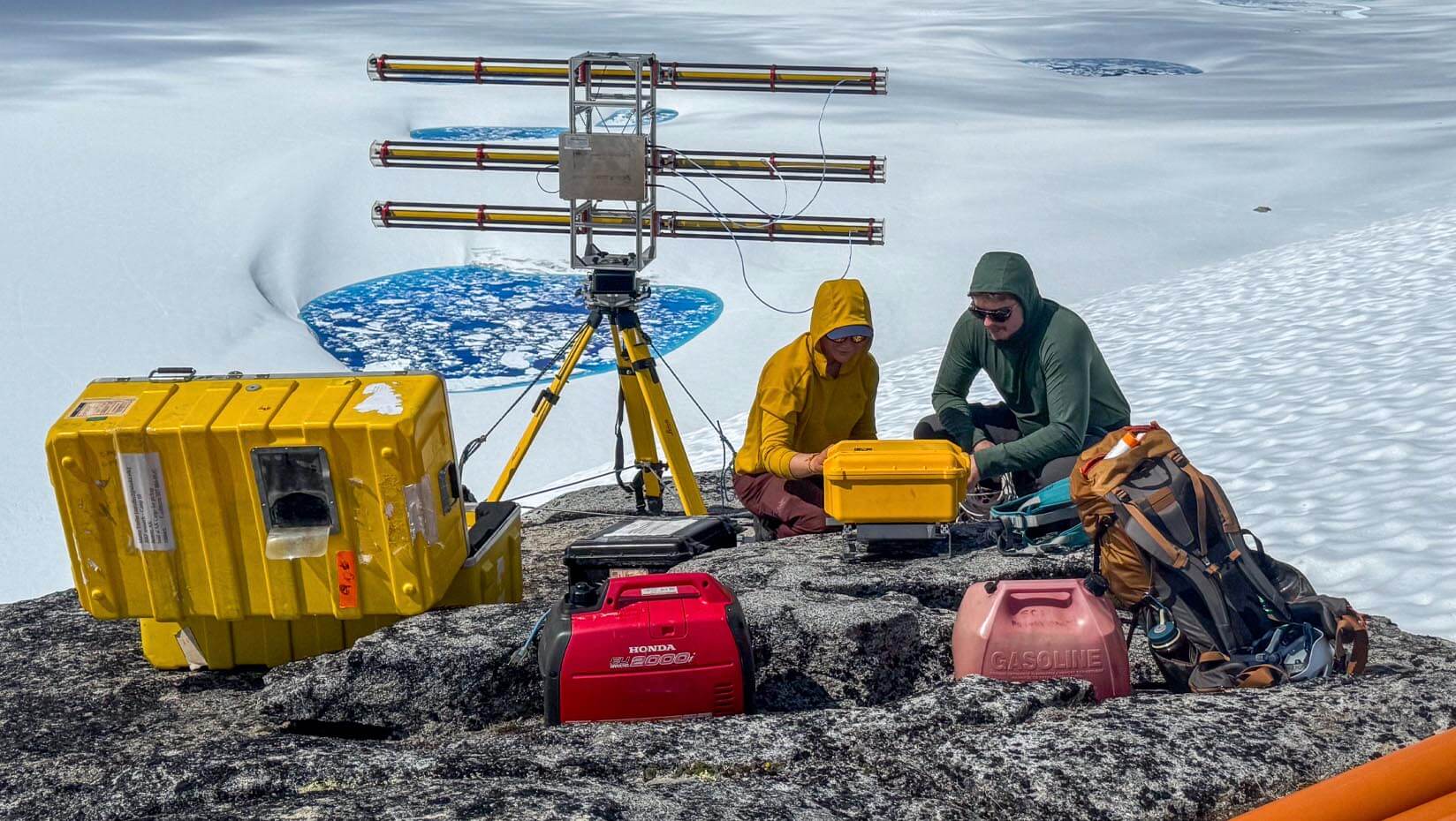 A photo of two people working with equipment in the snow