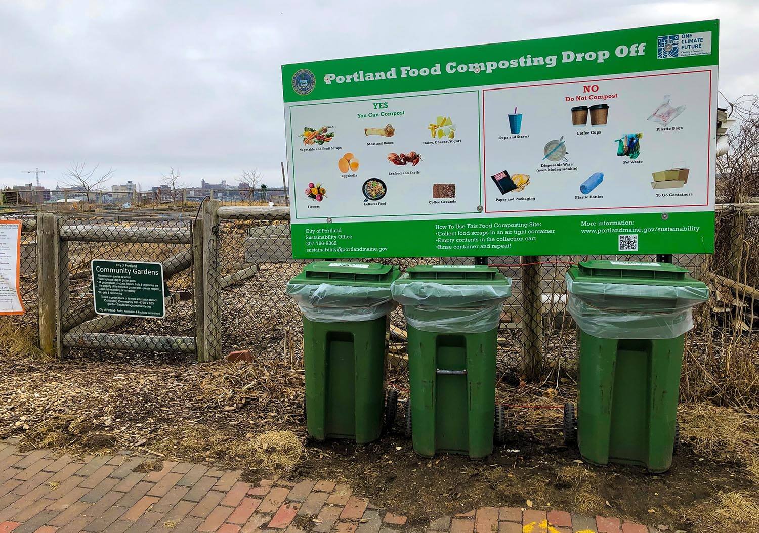 A photo of a sign explaining what foods can be composted and three collection bins