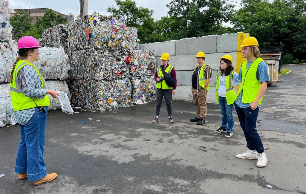 A photo of people wearing hard hats and bright vests near recycled gooods