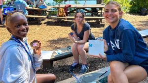 A photo of three students holding up craft projects