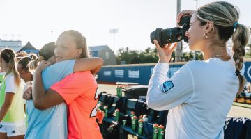 A photo of a person talking pictures of athletes during a game.