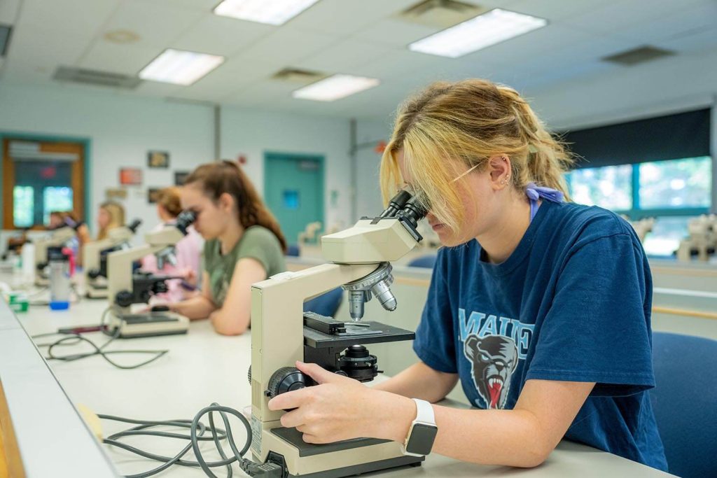 A photo of people in a lab class using microscopes