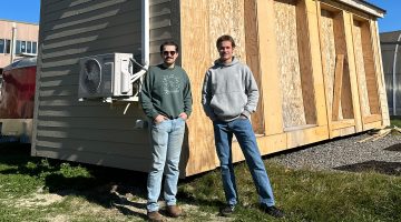 Photo of two people standing in front of a house.