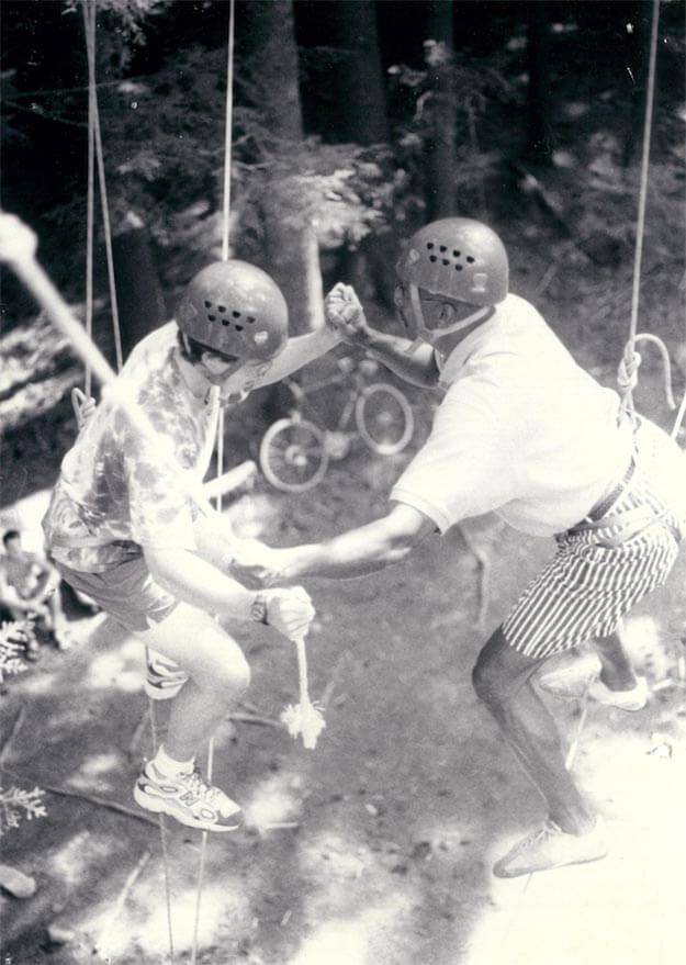 A photo of a person helping someone balance on a tightrope