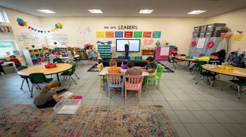 A photo of a children and a teacher in a classroom.