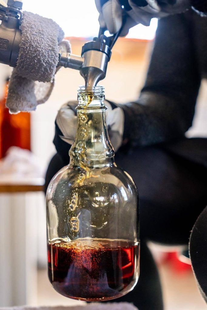 A photo of maple syrup being poured into a glass bottle