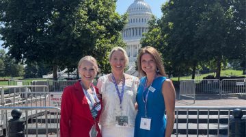 Three people smile and pose for a photo outside of the U.S. Capital Building in Washington, D.C.