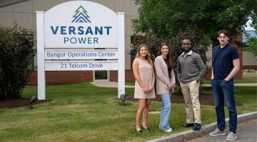 Four people pose for a photo outside of the Versant Power Bangor Operations Center.