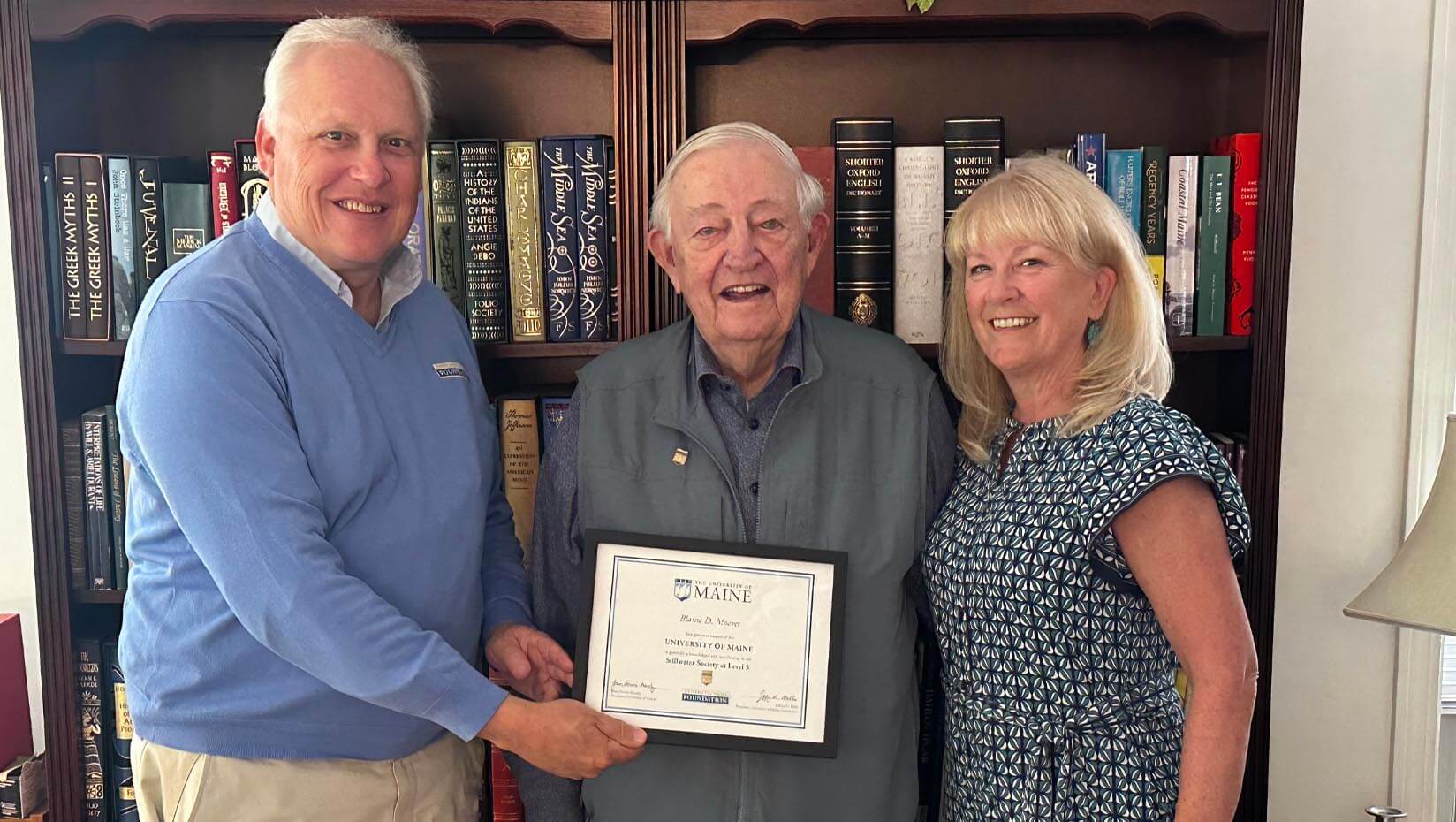 A photo of three people with a framed certificate