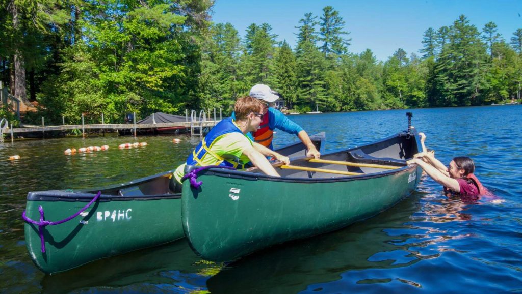 A photo three people using canoes on a lake