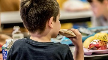 A photo of a child eating lunch at a school