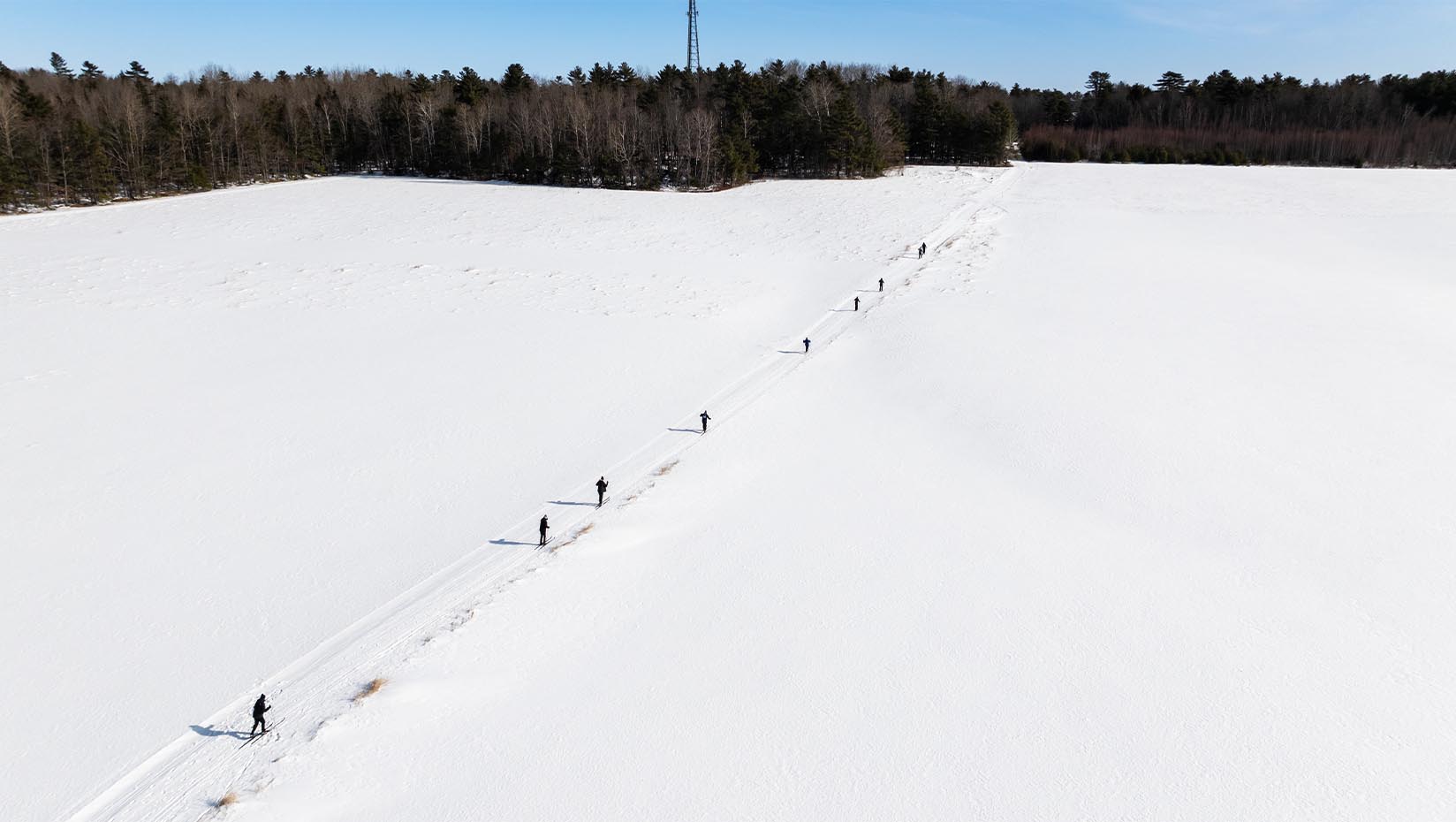 An aerial photo of people skiing across a snow-covered field.