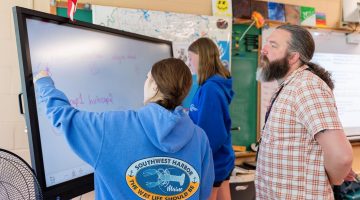 A photo of three people in a classroom.