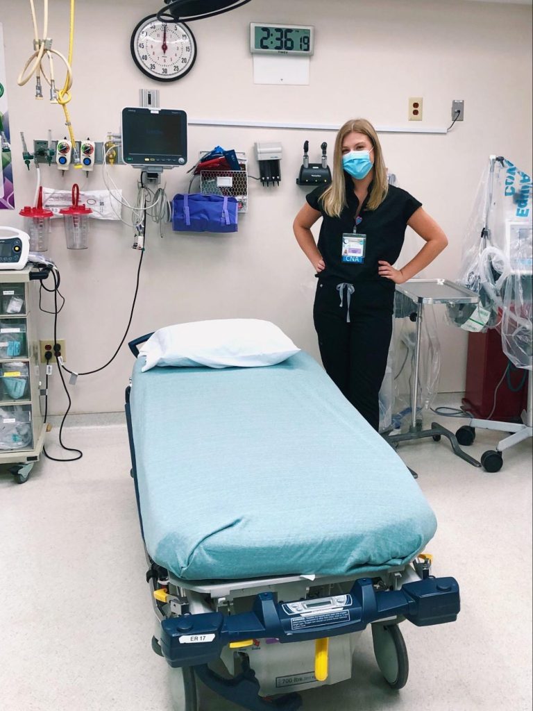 A photo of a nursing student next to a hospital bed