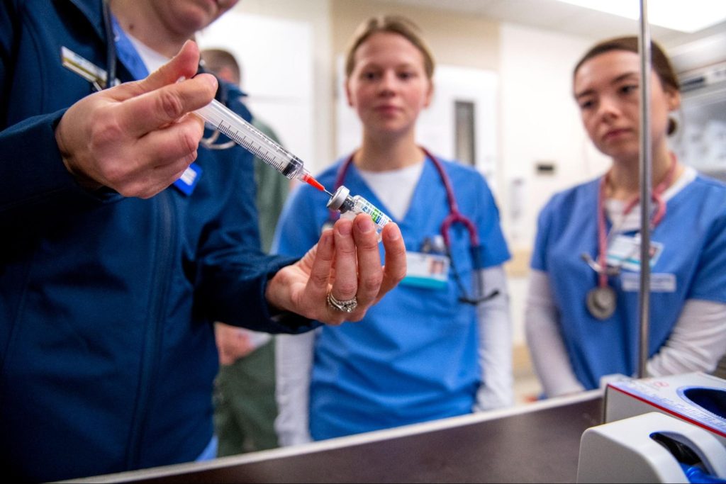 A photo of nursing students with a syringe