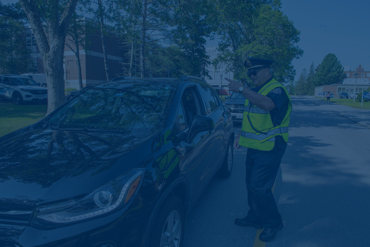 A photo of UMaine police directing traffic with a blue overlay. Link to UMaine Police Department website