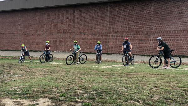 Group of people on bikes in front of brick wall