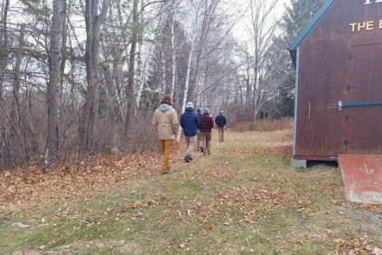 a group of students walks past a barn
