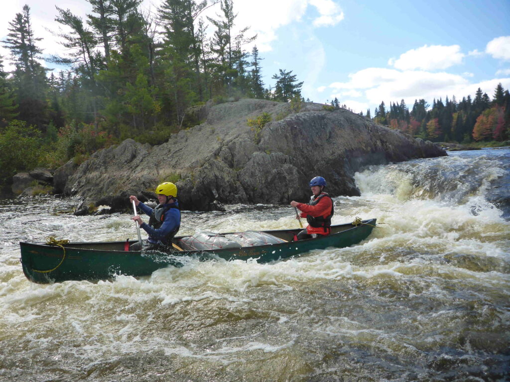 Canoe with paddlers in whitewater.