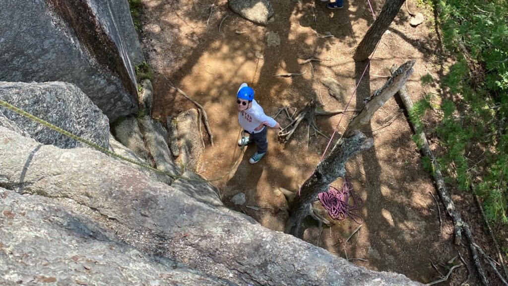 Rock climber standing at bottom of cliff face.