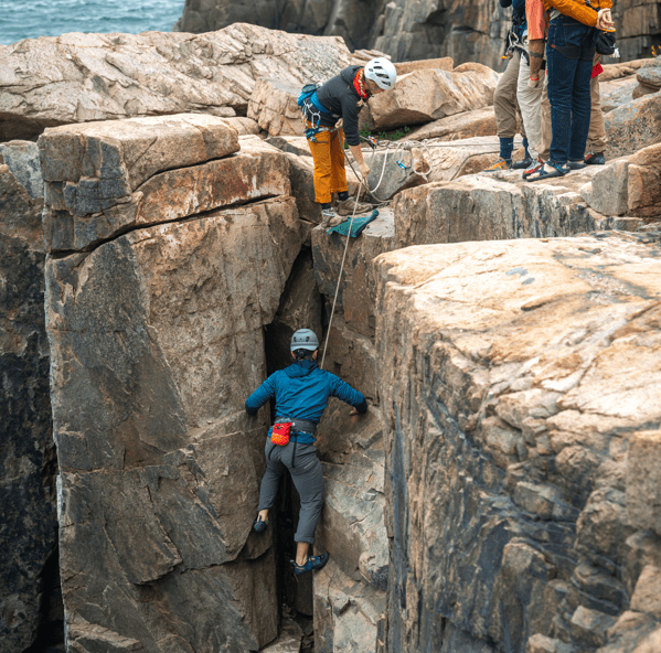 Rock climbers ascending cliff face.