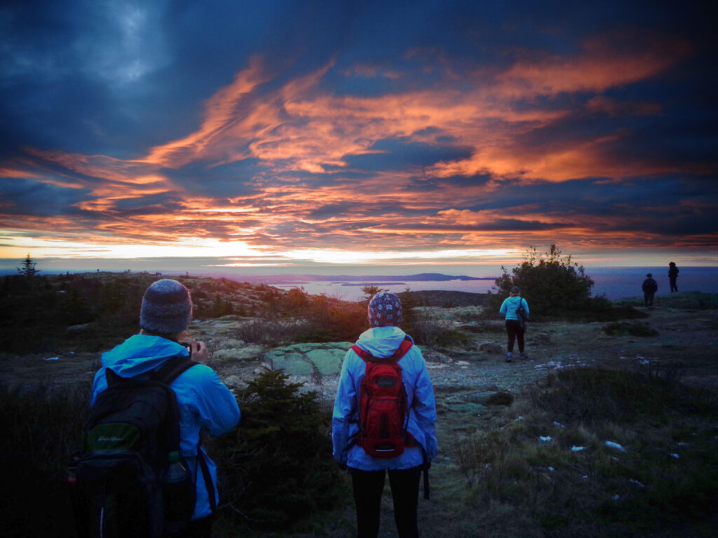 Hikers viewing sunset along a coastal trail.