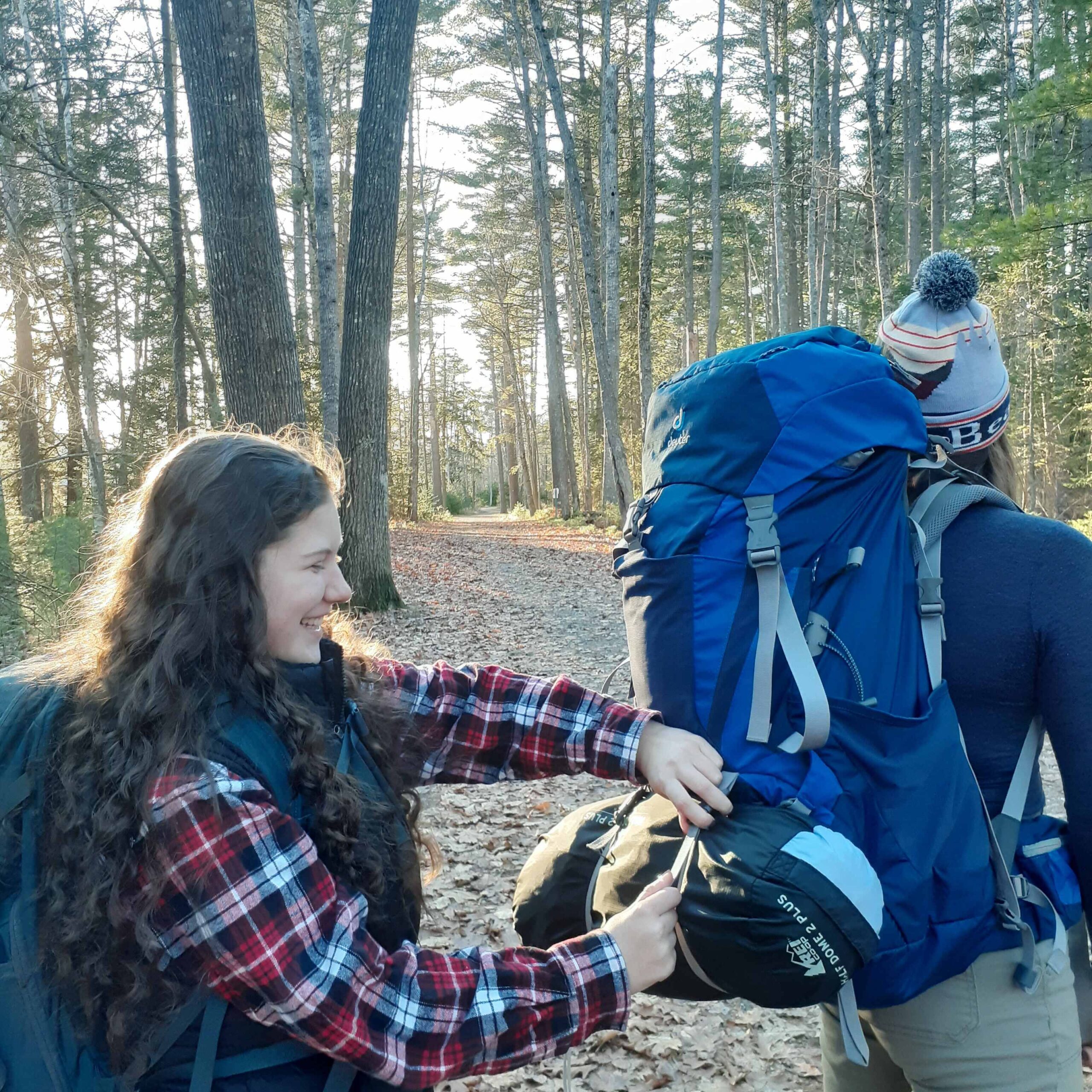 Backpack leaning against tree with coastal sunset in background.