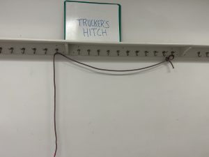 Rope hanging off of hangers below a sign that says 'trucker's hitch'