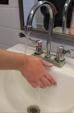 Student running their arm under a faucet.