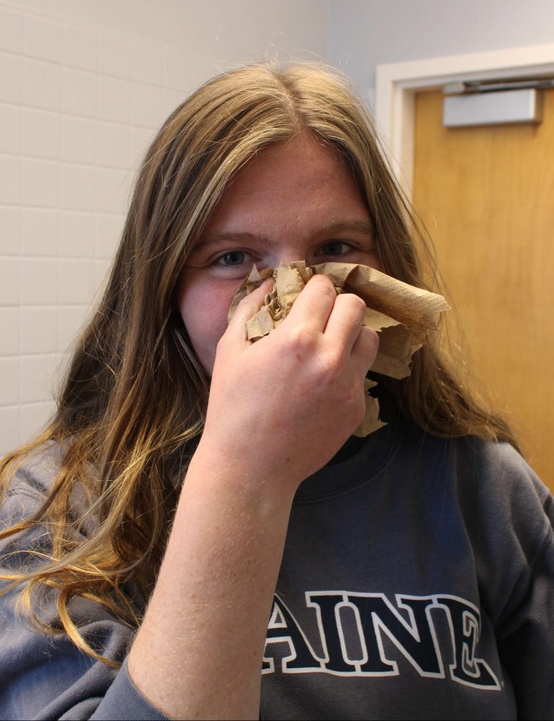 Student holding a clean dressing to the bridge of their nose.