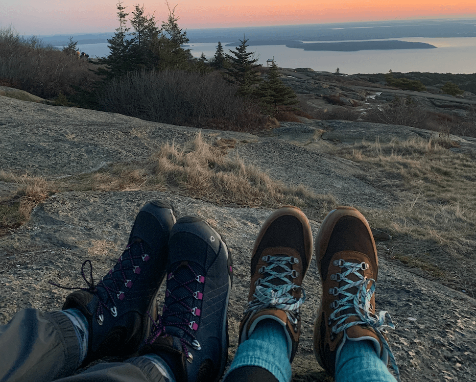 Two pairs of hiking boots onto of a mountain landscape