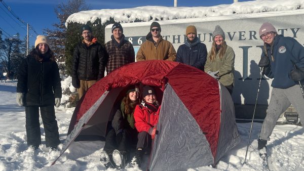 Photo of nine UMaine students in the snow with a tent