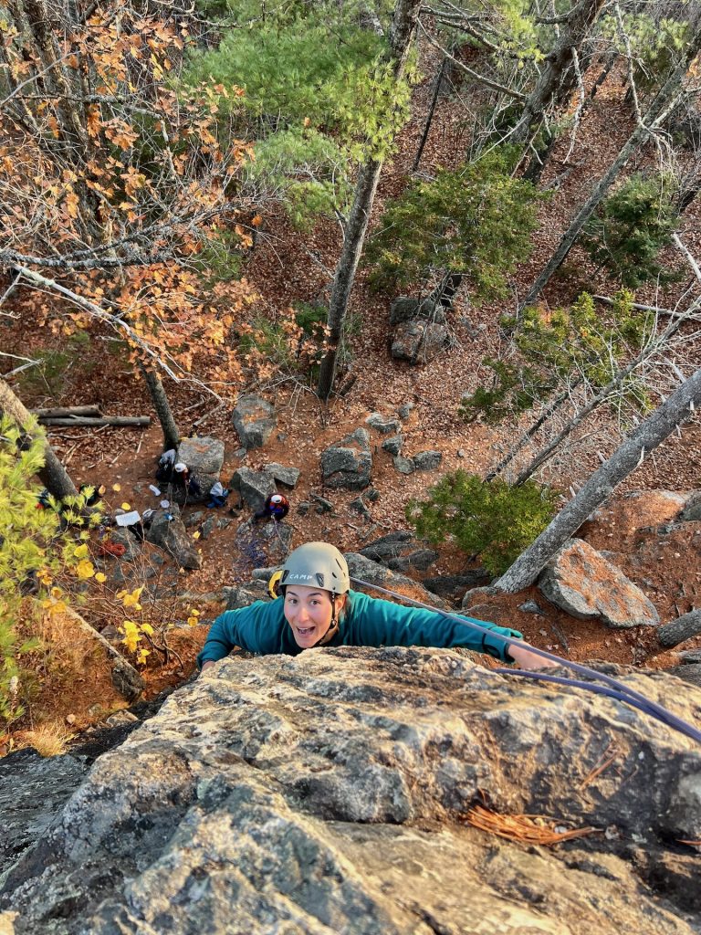 Woman climbing on a rock wall outside.