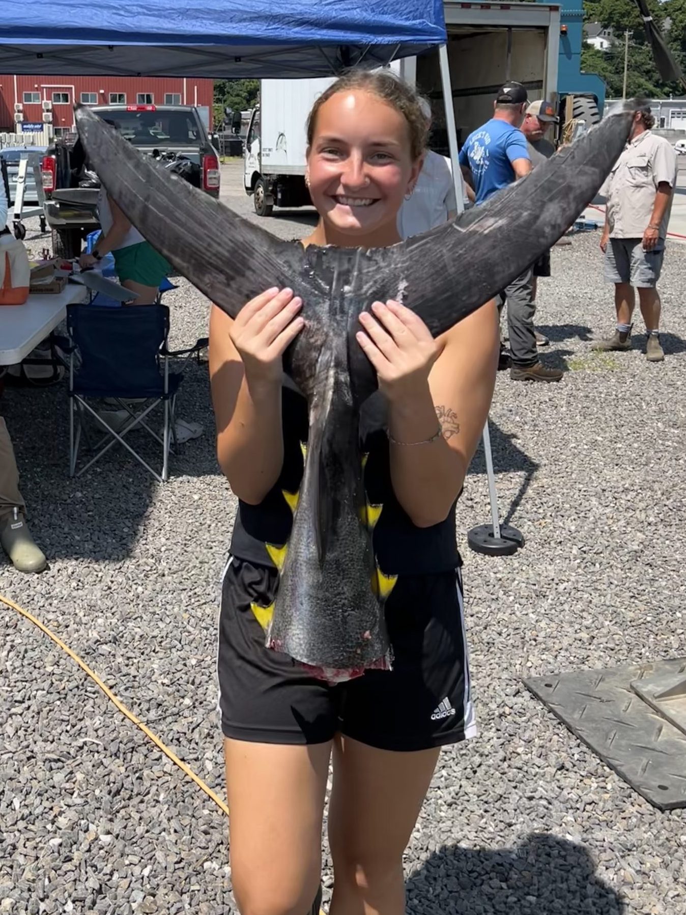 Emma Fortin, University of Maine Pelagic Fisheries Lab intern, hold an Atlantic bluefin tuna tail at the Bluefin Benefit Battle.