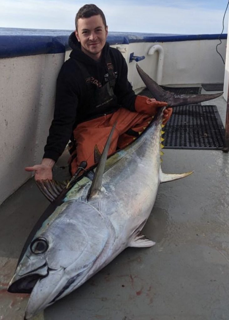 Riley Austin, previous Graduate student, holding a Yellowfin tuna on a pelagic long liner.