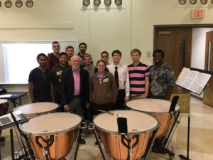 stuart marrs posing with students in from of timpani