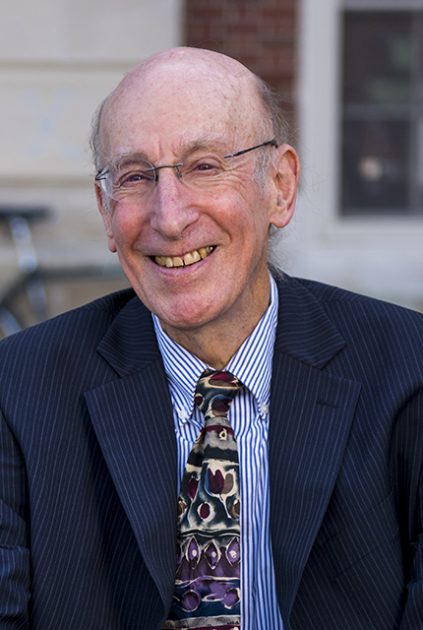 A smiling older man (Doug Allen) in a blue suit.