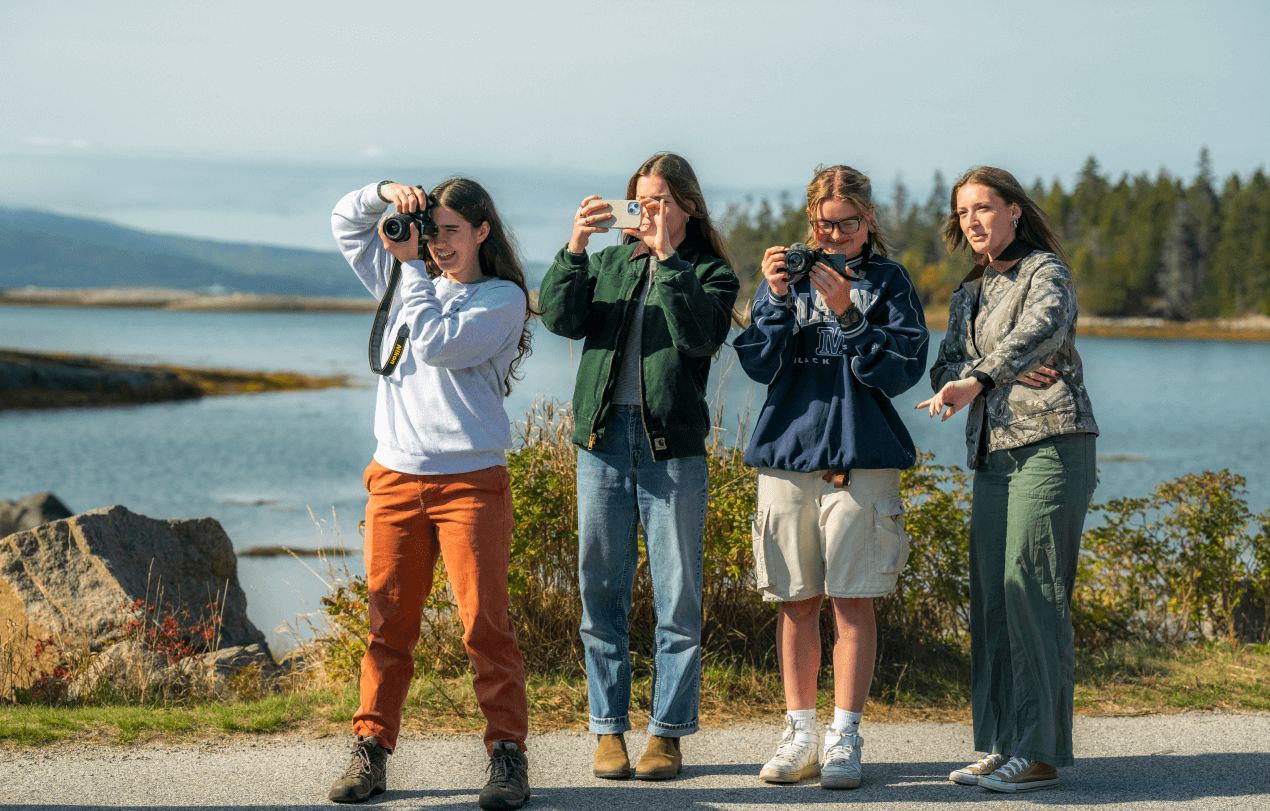 A photo of four people with cameras on Maine's coast