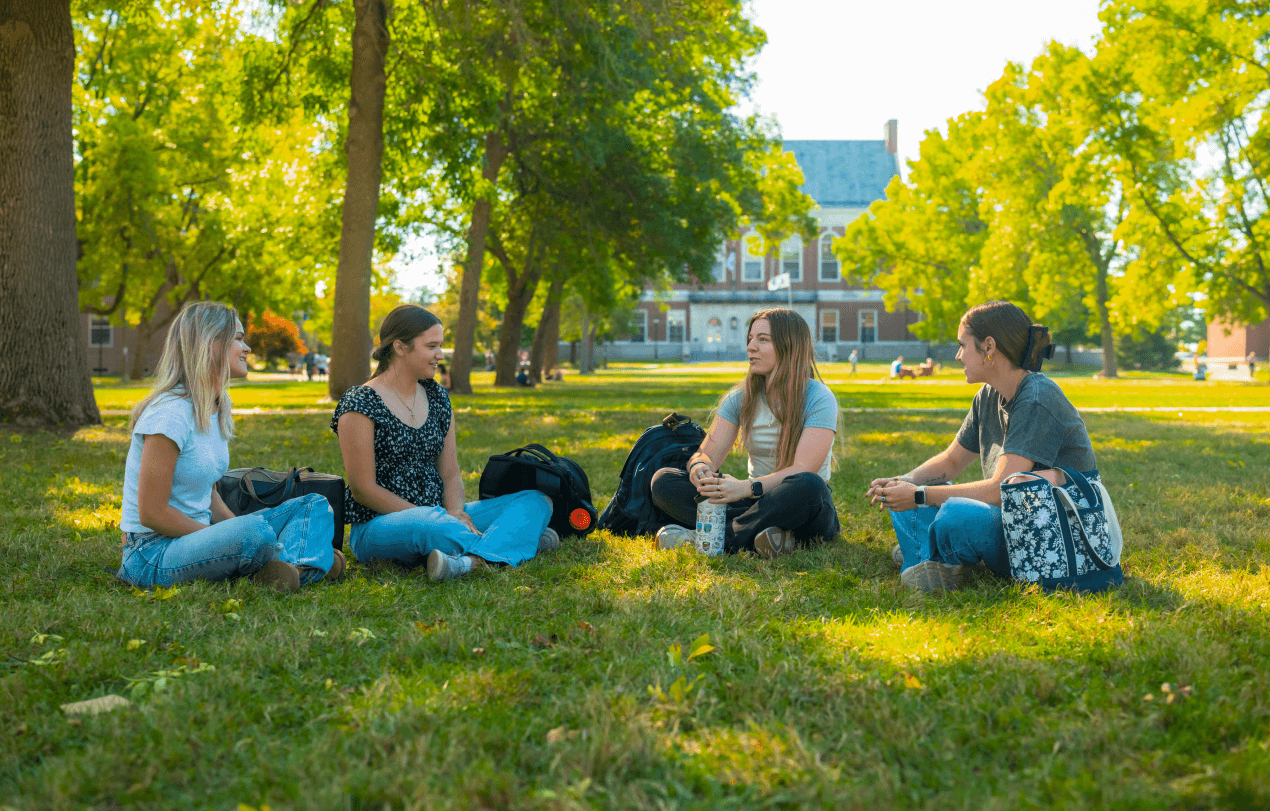 A photo of four people sitting on UMaine's Mall