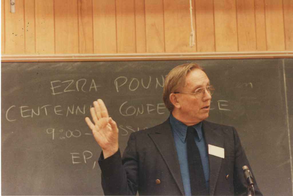 Photograph of Burt Hatlen in front of a chalkboard representing an Ezra Pound Conference