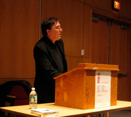 Alan Halsey reading behind a podium looking at the audience out of frame