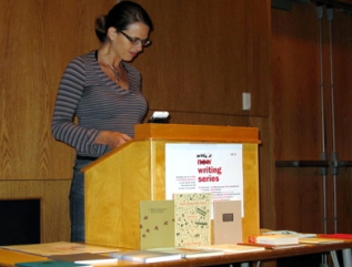 Anna Moschovakis reading aloud behind a podium