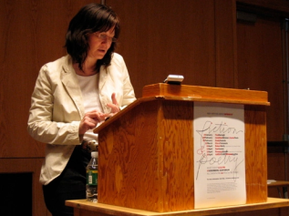 Brenda Coultas reading aloud behind a podium