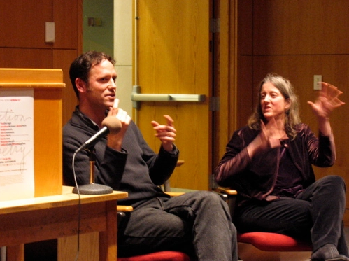 Jonathan Skinner and Annie Finch sitting while talking with each other next to a podium