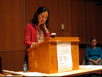 Sawako Nakaysau reading aloud to audience behind a podium