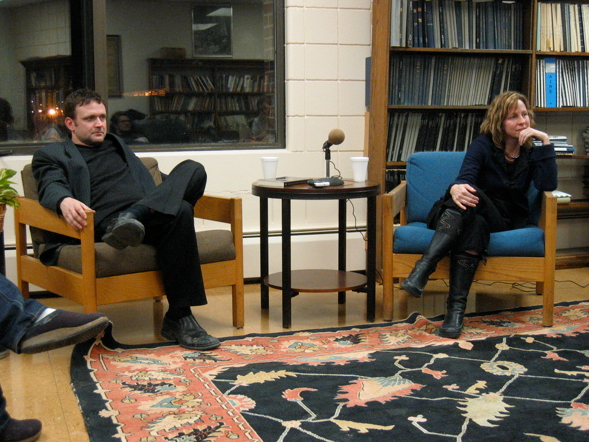 Stephen Cope and Catherine Taylor sitting in chairs in front of a bookcase and a window talking to someone out of frame