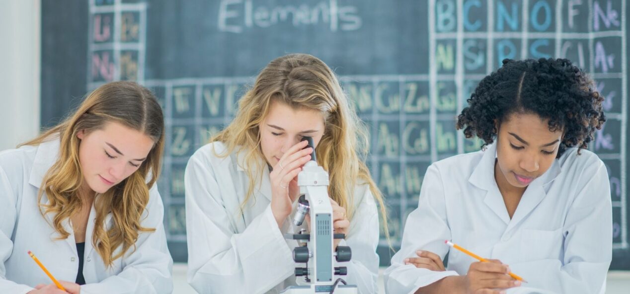 Three female students using a microscope