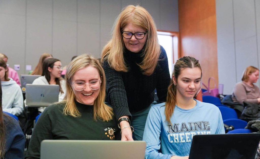 A photo of a professor and two students in a classroom