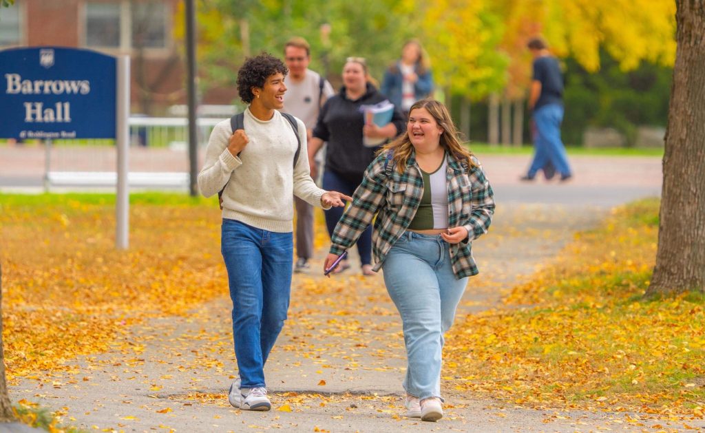 A photo of two people walking in fall on campus