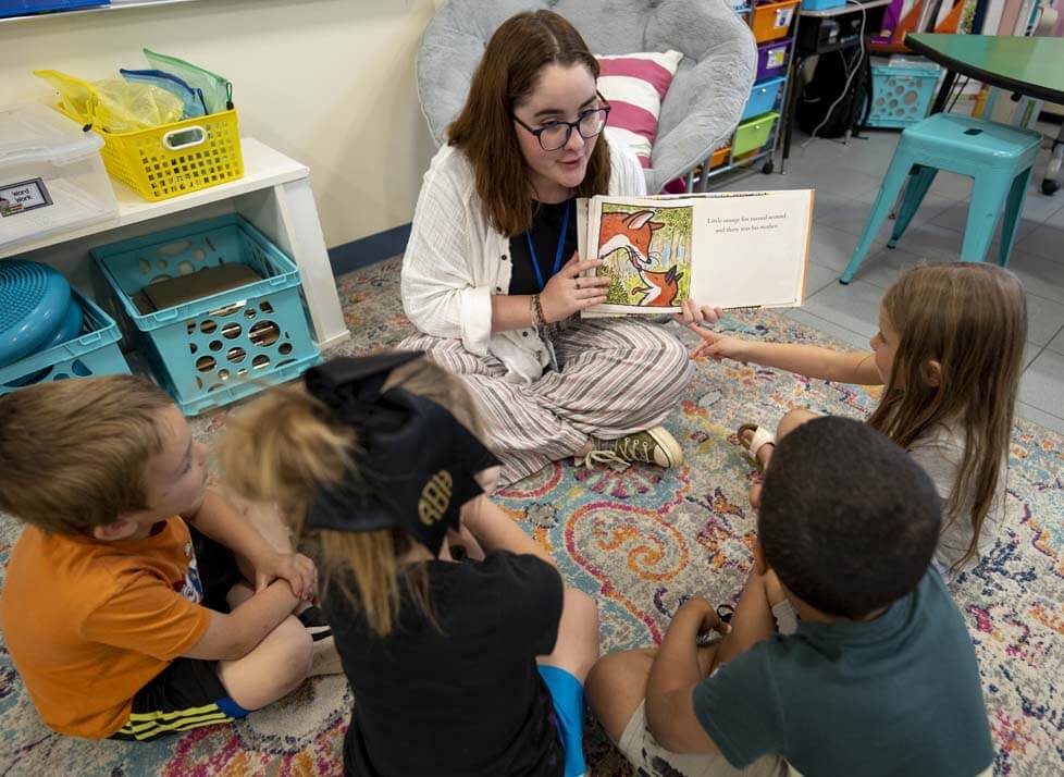 A photo of a student-teacher working with young students